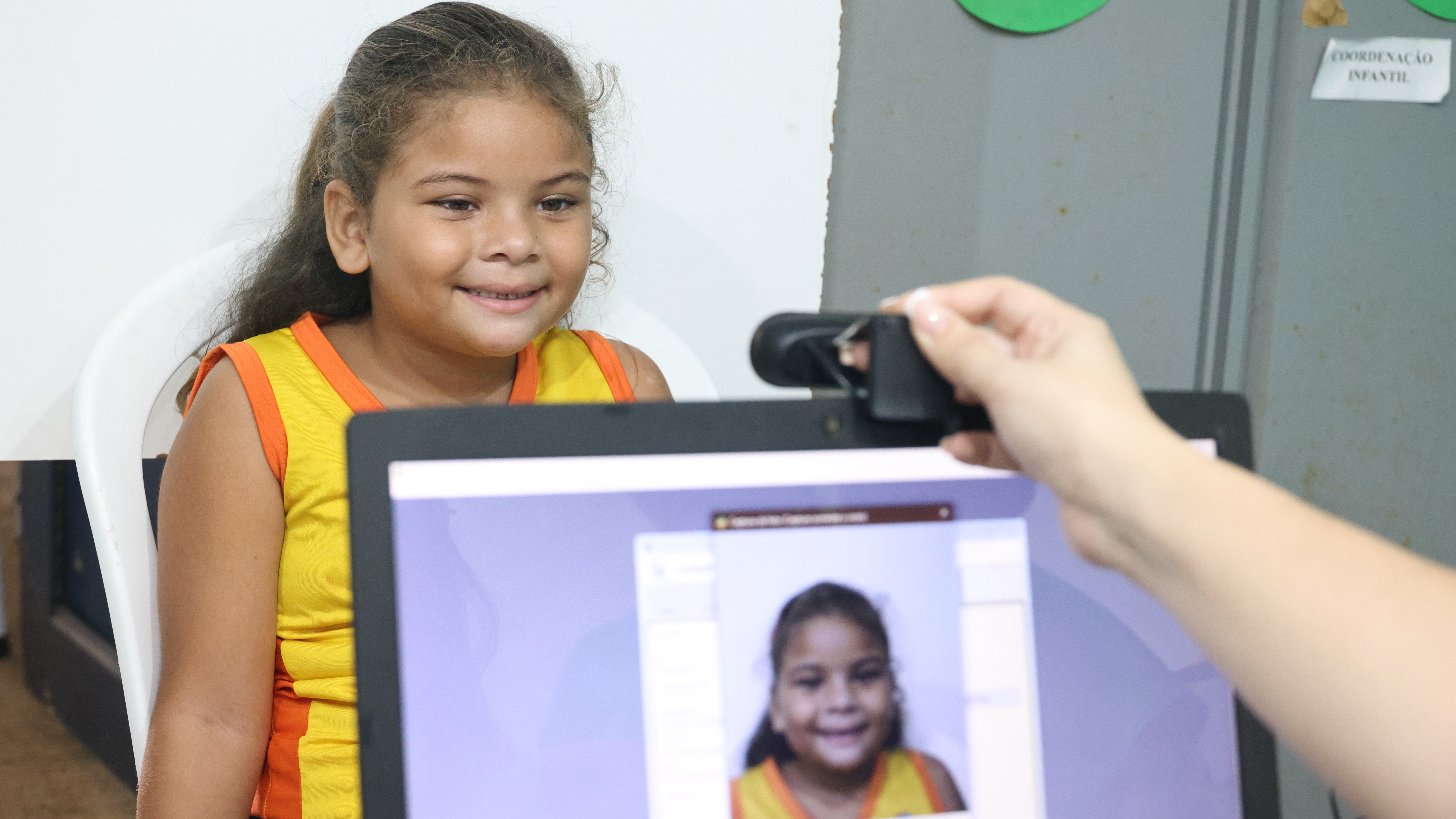 aluna tira foto digital para a emissão do passe livre da criança